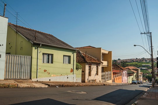 Downhill street view with sidewalk walls and colorful houses on a sunny day at São Manuel. A cute little town in the countryside of São Paulo State. Southeast Brazil.