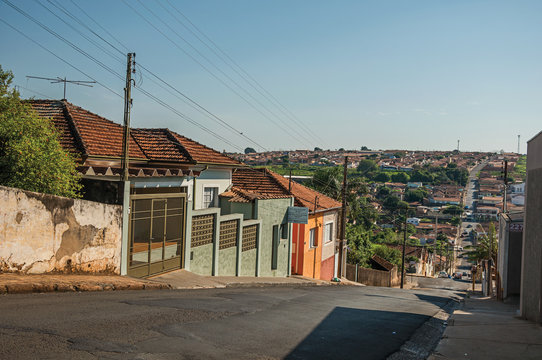 Downhill street view with sidewalk walls and colorful houses on a sunny day at São Manuel. A cute little town in the countryside of São Paulo State. Southeast Brazil.