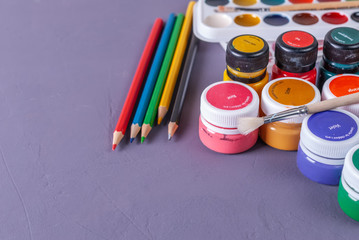 Multicolored jars with paint for paint, brush and colored pencils