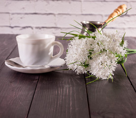 Cup of coffee, macaroons on a plate and a bouquet of flowers.