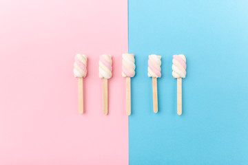 Marshmallows on sticks on tender pink blue background