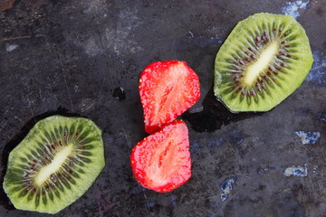 Strawberry and kiwi on a dark metallic background, red berries and sliced kiwi on a vintage...
