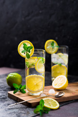 Lemon fruit lime slices caipirinha from Brazil, lemonade mint ice cubes in cold glasses on dark...