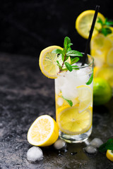 Lemon fruit lime slices caipirinha from Brazil, lemonade mint ice cubes in cold glasses on dark background, alcoholic mojito cockail ice tea green mint leaves, brown sugar spoon, copy space