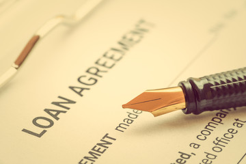 Fototapeta premium Business loan agreement or legal document concept : Fountain pen on a loan agreement paper form. Loan agreement is a contract between a borrower and a lender, a compilation of various mutual promises.