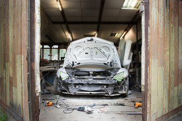 white broken assorted dusty car stands in the garage