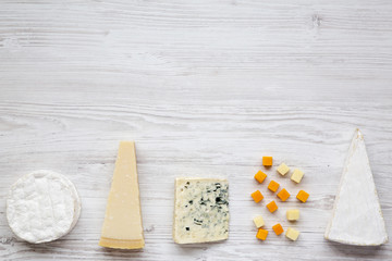Assortment of various cheese on a white wooden background with copy space. From above, flat lay.