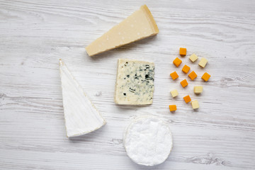 Different kinds of cheeses on white wooden table