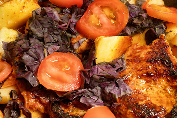 Fried meat, potato, basil and tomatoes close up