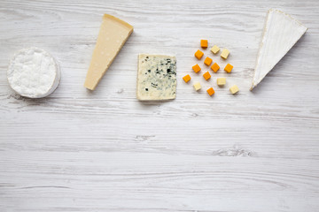 Different kinds of cheeses on white wooden table. Copy space. Top view.