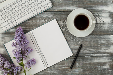Office desk table with computer, supplies, cup of coffee and peony flowers. White wooden...