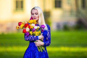Fototapeta premium Positive Caucasian Blond With Bunch of Tulips. Posing Outdoors.