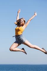 Carefree woman jumping by sea ocean water.