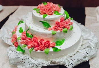 Festive white cake with decor. A wedding cake. Red roses.