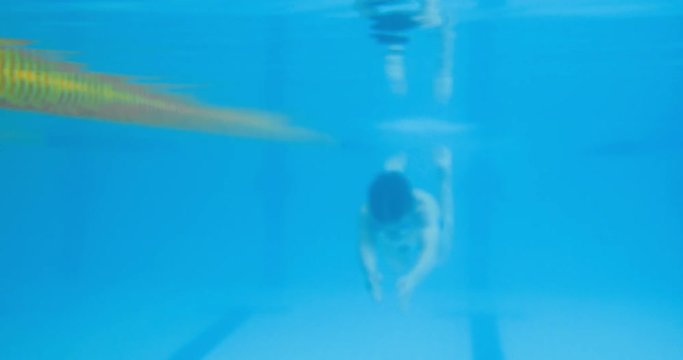 Professional swimmer boy swims under the water in the pool. Underwater shooting