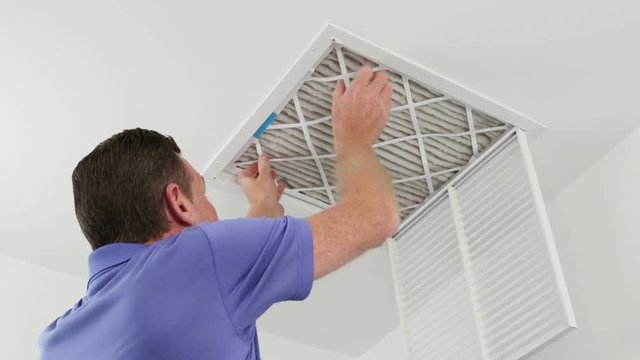 Man Replacing Ceiling Air Filter 
Mature male replacing a dirty air filter with a clean one in a HVAC return duct. Technician changing a dirty air filter for a clean one in a ceiling home air duct.