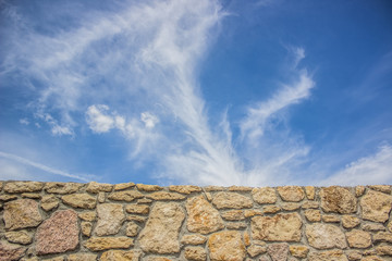 old stone wall and blue sky clouds concept with empty space for copy or text
