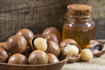 Nuts and macadamia oil on wooden background - Macadamia integrifolia