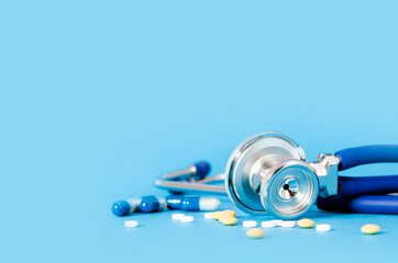 Stethoscope and pills on blue background