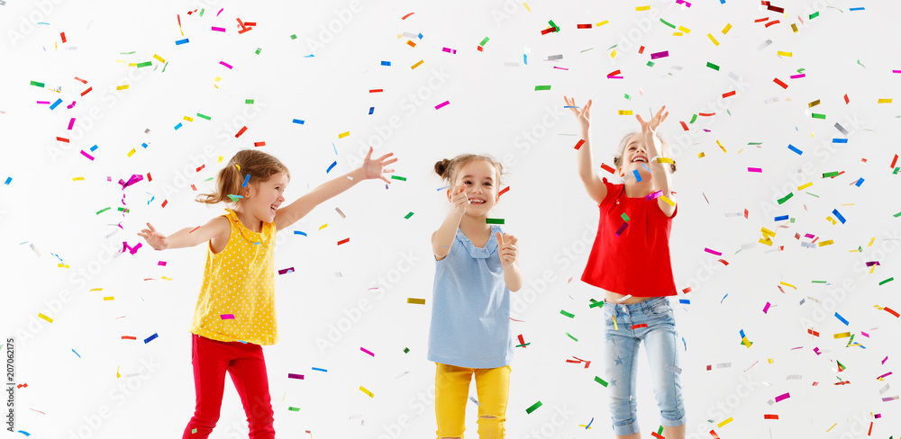 Wall mural happy children on holidays jumping in multicolored confetti on white