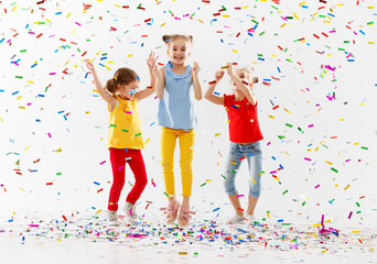 happy children on holidays  jumping in multicolored confetti on white