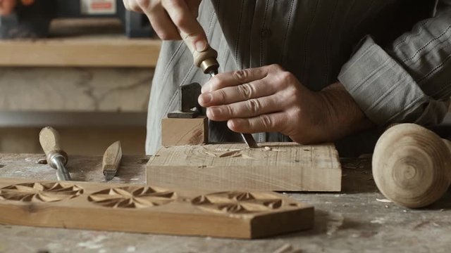 Professional skilled carpenter carving wood with a gouge