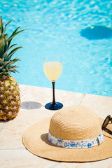 straw hat  cocktail and pineapple by the pool - summer holiday concept