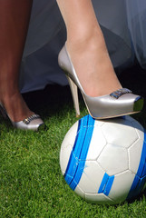 bride's foot in shoes on top of a soccer ball at football field