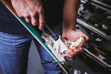 Theme tincture and repair ski equipment ski. Close-up of a Caucasian man's hand use a hand-held screwdriver tool to tweak, twist bindings for ski boots in the workshop