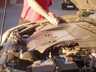 close up man repairing the car with opened hood