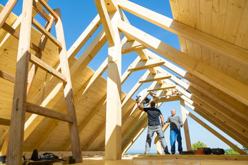 Roof builders mounting prefabricated wooden roof construction. Construction industry concept.