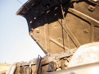 close up opened hood of the car against the sky