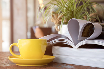 Close up of yellow coffee cup placing together with magazine like Heart Shape