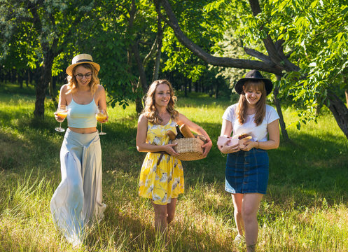 Group of girls friends making picnic outdoor. They choose location and drink cocktail