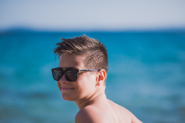 Young kid with sunglasses posing on the beach