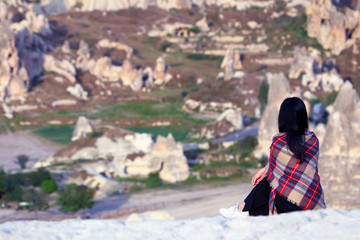 Fototapeta na wymiar girl from a hill looks at the volcanic rocks in the valley of Cappadocia, Turkey