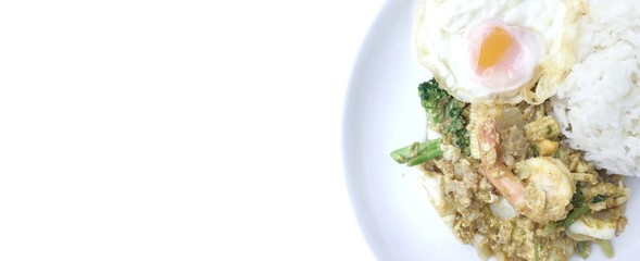 Stir-fried prawns, squi and mixed-seafood with yellow curry powder and thai herb vegetables with rice and fried egg in white plate on white background. Thai style food.