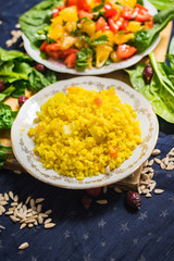 Cooked bulgur porridge pilaf or pilau served with raw vegetables salad. Yellow turmeric meal. Vegan vegetarian healthy food. Traditional Arabic asian food