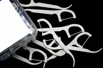 close up tooth picks and dental floss on a black background