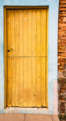 Yellow door on blue and brick wall