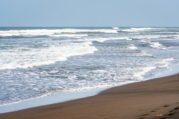 Waves breaking on a sandy beach with blue sky in the background, as a nature background, Caribbean Sea in Costa Rica
