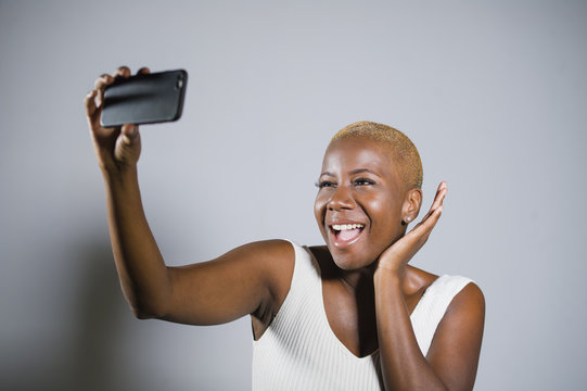 young beautiful and happy black afro American woman smiling excited taking selfie picture portrait with mobile phone or recording self portrait video