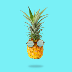minimal concept. Cute and funny pineapple with sunglasses over mint background.