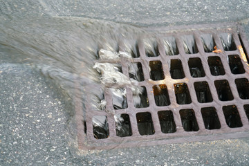 close up on rain water flowing into manhole on the street