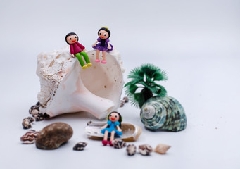 In selective focus of the couple miniature,beauty girl and handsome boy,sitting on seashell,blurry light design background