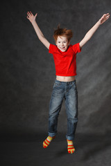 Red-haired boy jumping on a dark background. Studio photography