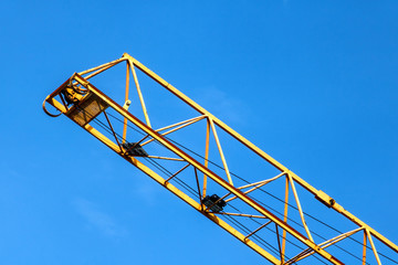 The crane arm with the hoist work on a blue sky background