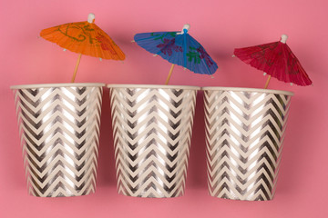 top view three paper cups with cocktail umbrella pink background , summer party or summer sale concept