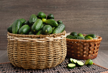 Cucumbers in two wicker baskets. Vintage of green fresh cucumbers in large wicker baskets on a wooden background. Vegetables collected in the garden.