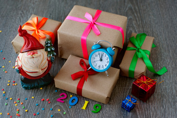 Pot-bellied Santa claus, watches and gifts for the new year 2019.
  Toy pot-bellied Santa Claus, Kraft paper gift boxes and an alarm clock for a fun new year 2019.